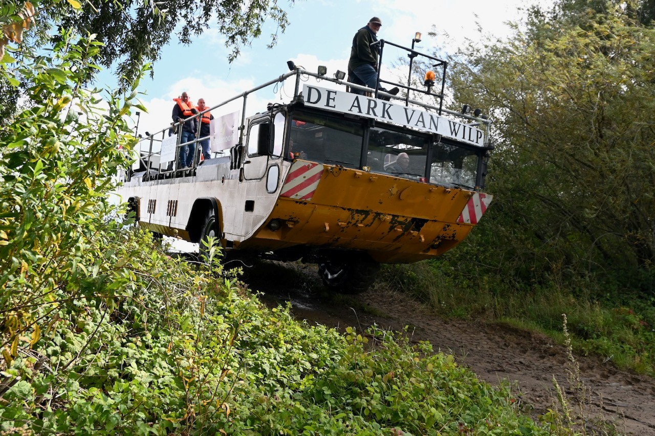 De Ark van Wilp rijdt het water uit de oever op, met passagiers aan boord