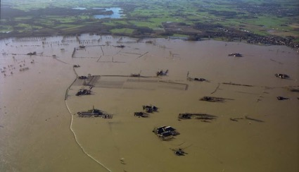 Luchtfoto van de ondergelopen Wilpse Klei: weilanden en boerderijen staan onder water